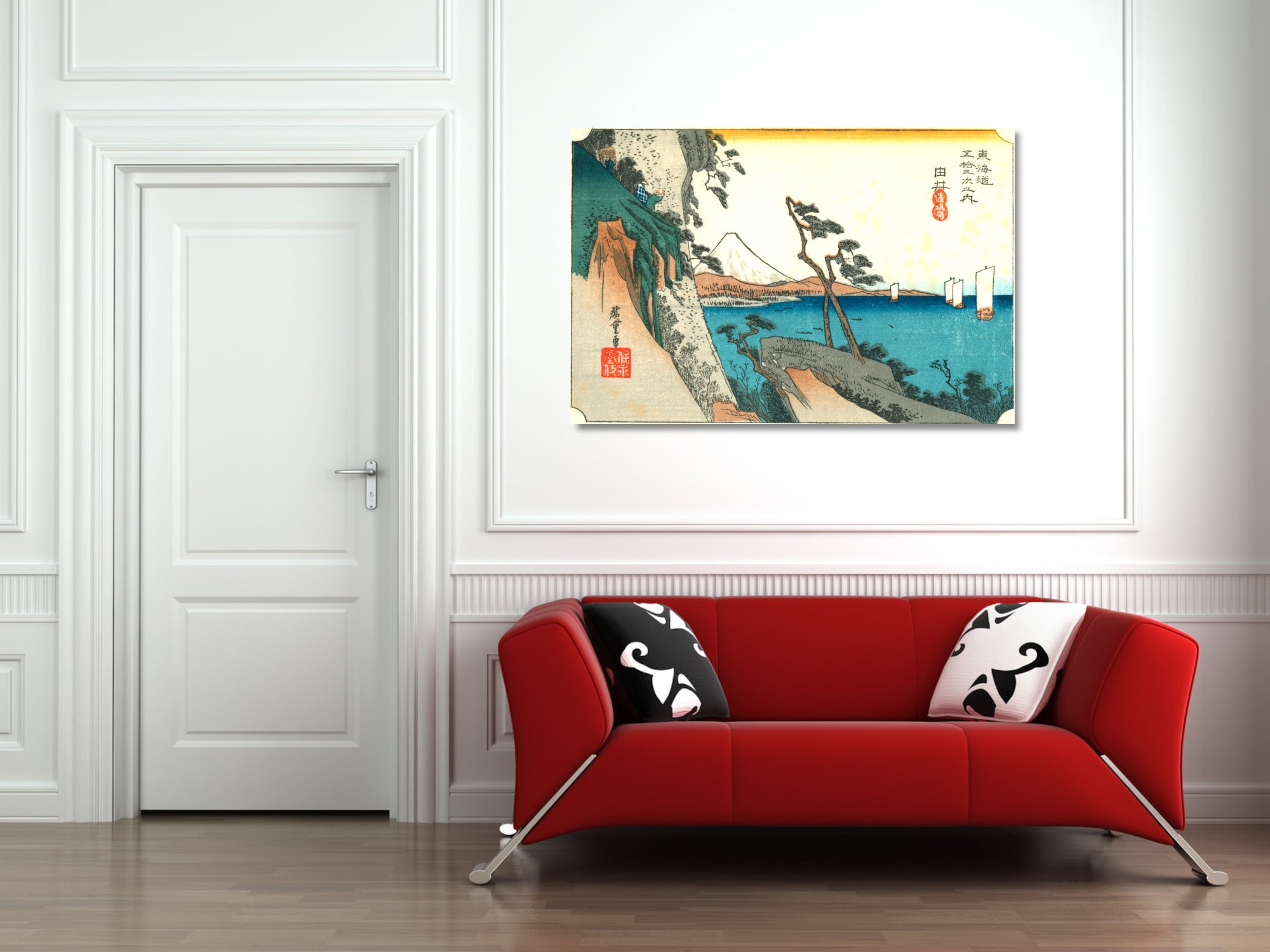 A framed Japanese-style landscape art print hangs on a white paneled wall above a red sofa with black and white patterned pillows in a modern living room setting.