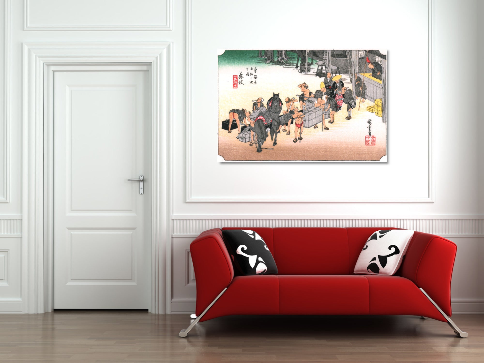 A framed art print depicting a traditional Japanese street scene with people and horses, displayed on a white wall above a modern red sofa with black and white patterned pillows.