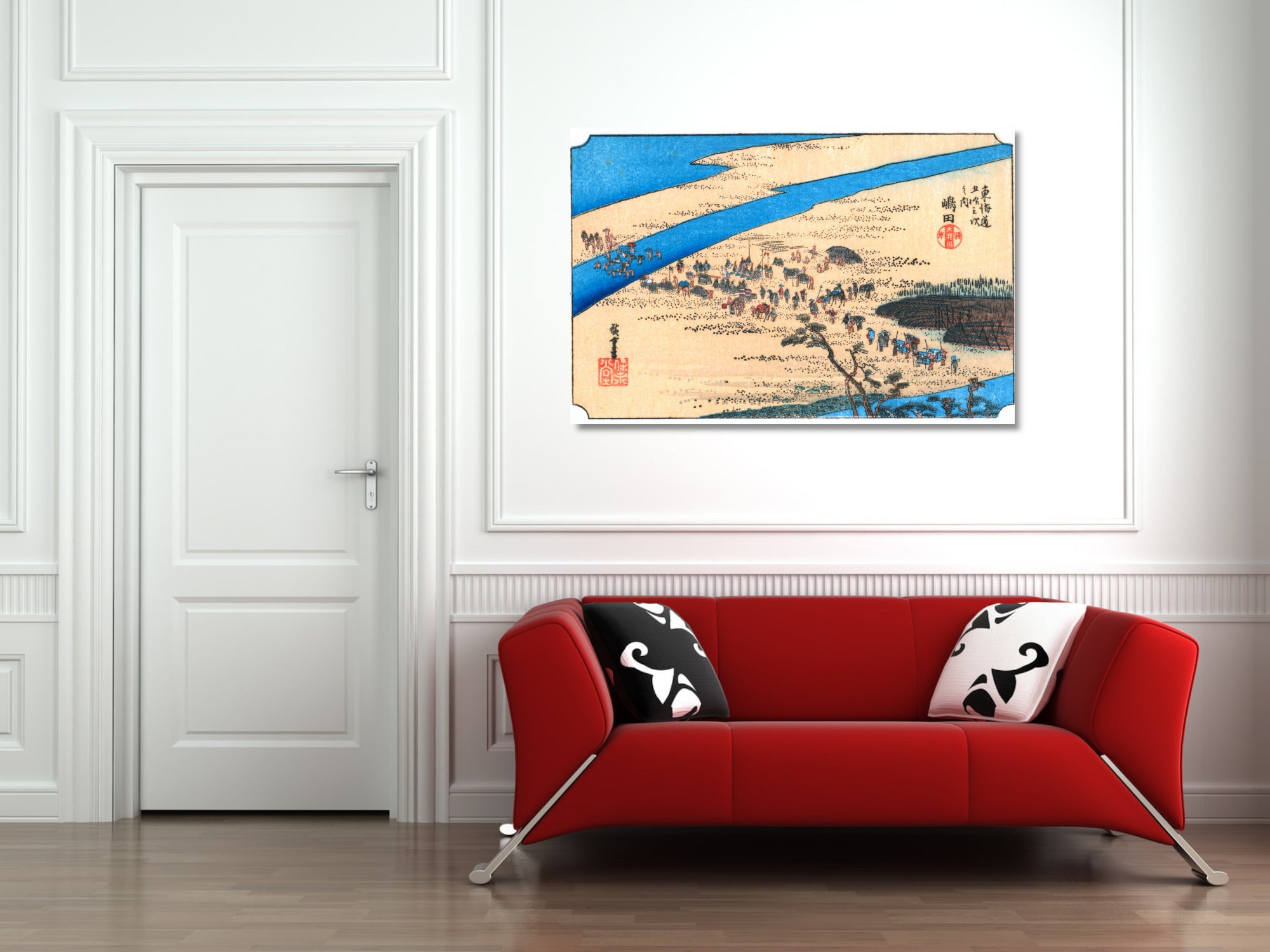 A framed Japanese-style landscape art print hangs on a white wall above a modern red sofa with black and white patterned pillows in a bright room.