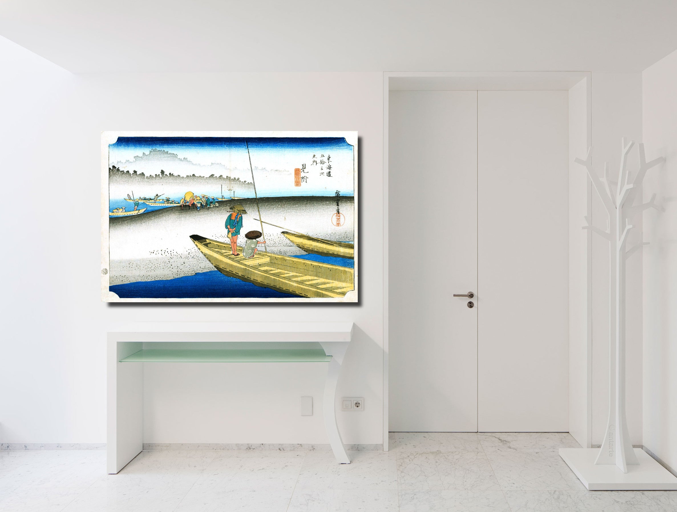 A framed Japanese ukiyo-e style art print depicting a fisherman in a boat, displayed on a white console table in a minimalist white room.