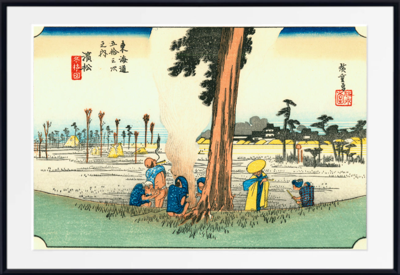 A framed Japanese-style art print showing a landscape scene with a large tree, figures near the base, distant buildings, and calligraphic markings, presented against a white background with a black frame.