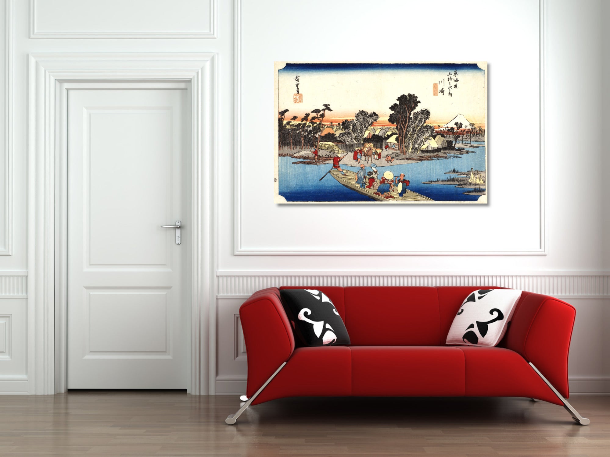 A framed Japanese ukiyo-e woodblock print depicting a river scene with figures and boats, displayed on a white wall above a red sofa in a modern living room setting.