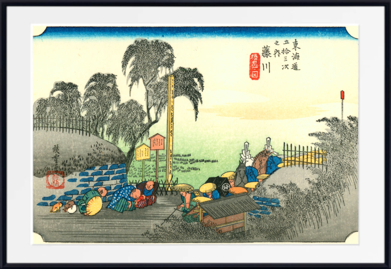 A framed Japanese ukiyo-e woodblock print showing a coastal scene with figures, trees, boats, and blue fish, presented with a white mat and black frame.