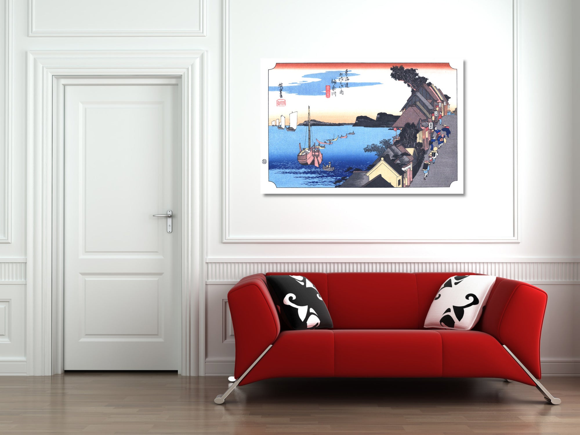 A framed art print of a Japanese ukiyo-e woodblock scene with boats and a harbor, displayed on a white wall above a modern red sofa with black and white patterned pillows.