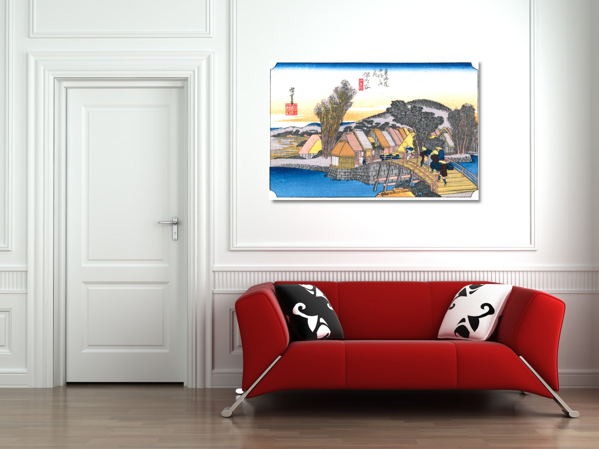 A framed art print of a Japanese ukiyo-e woodblock scene with a boat and figures, displayed on a white wall above a modern red sofa with decorative pillows.