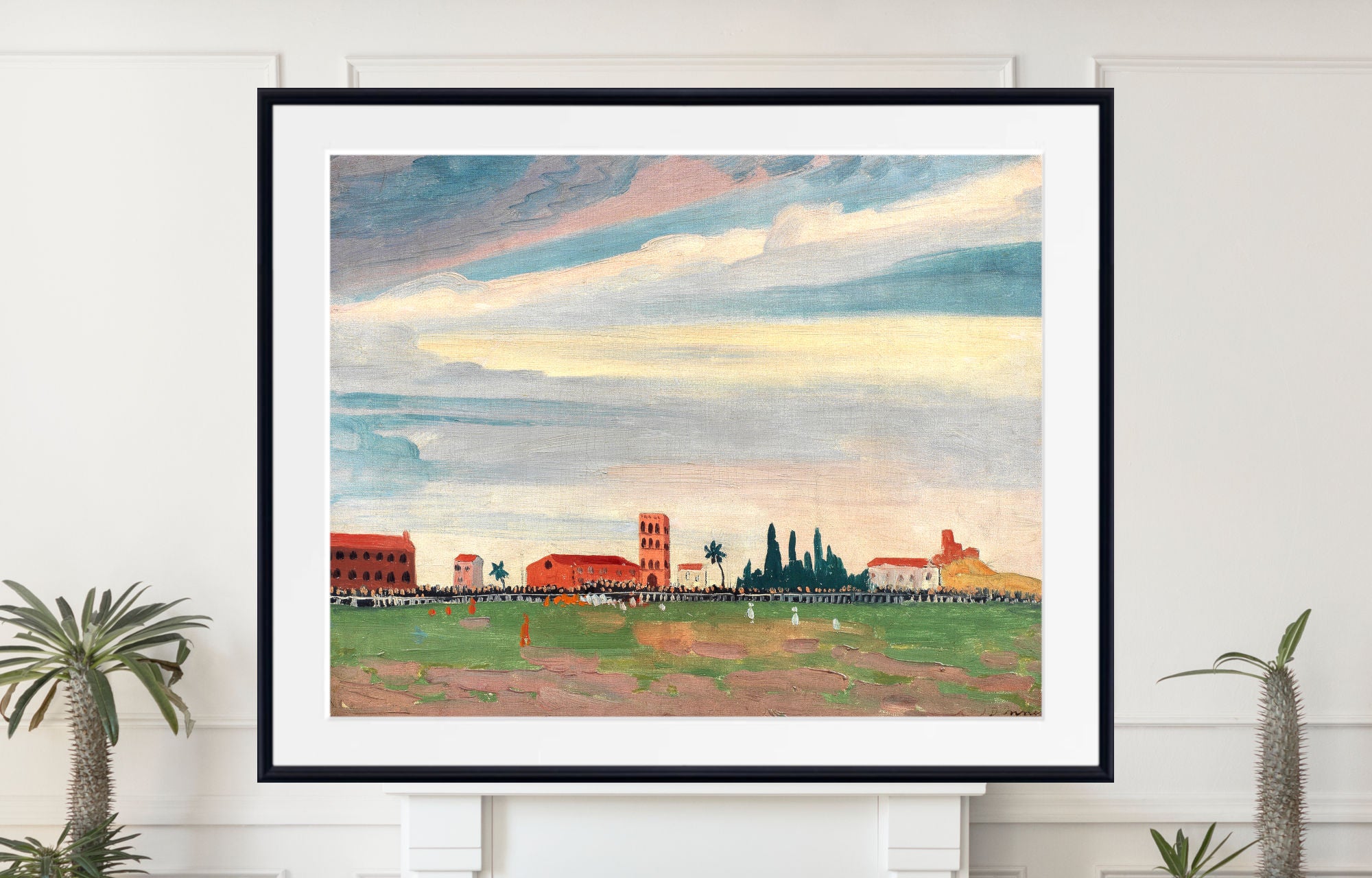 A framed art print featuring a landscape painting with a dramatic cloudy sky, red-roofed buildings, and a green field, displayed on a white wall above a mantel with potted plants.