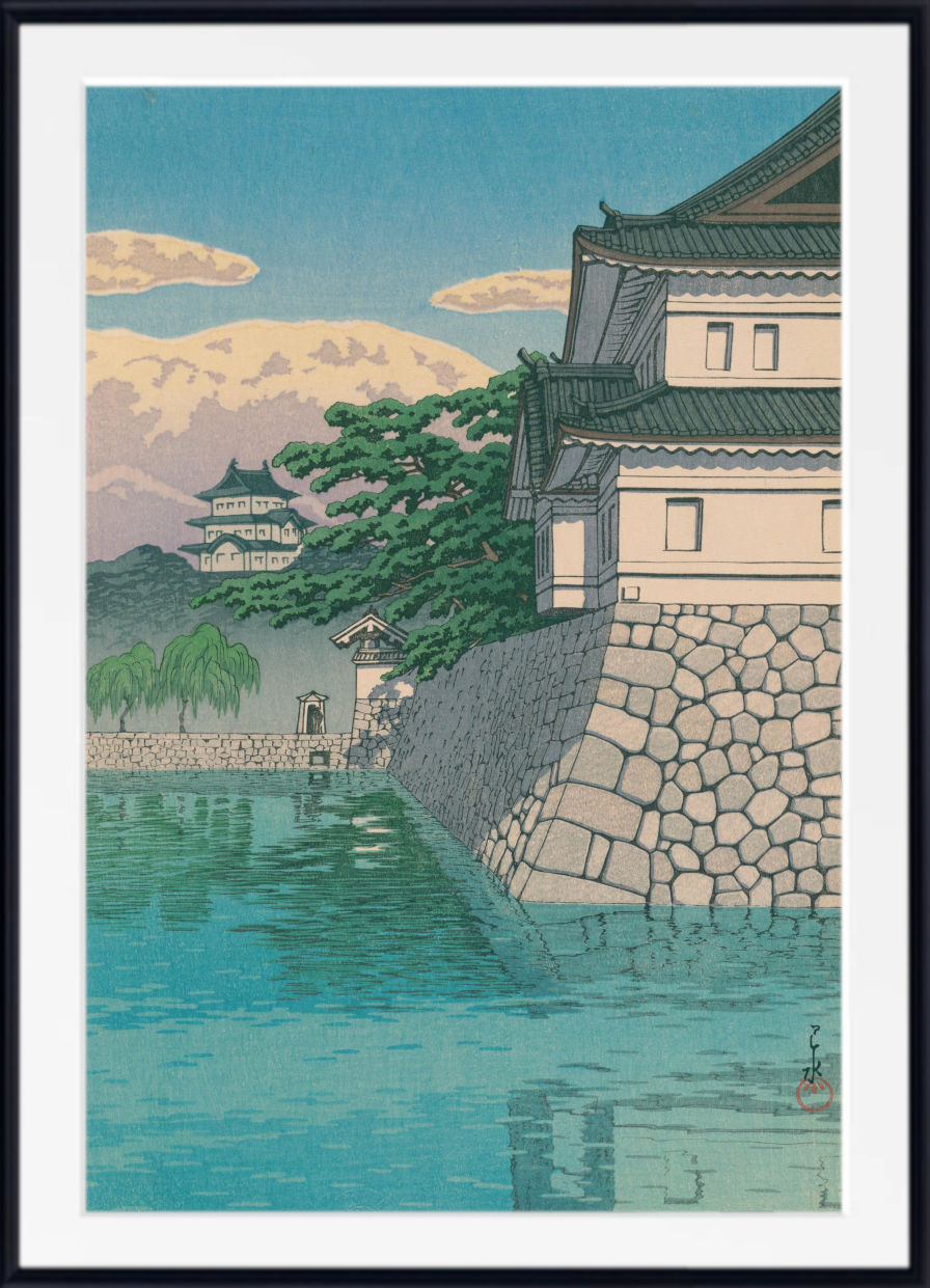 A framed Japanese-style art print depicting a stone castle wall, green trees, a pagoda, and blue water under a pale sky.