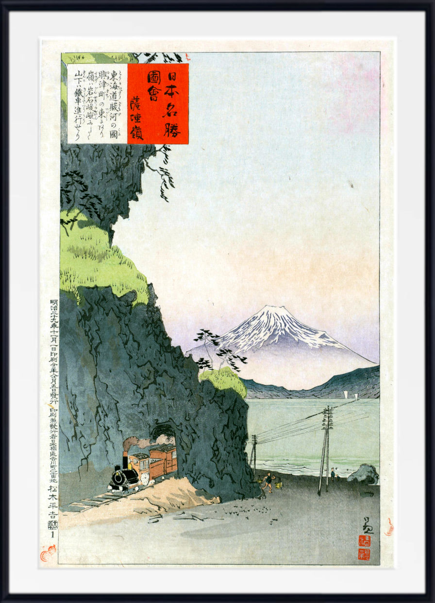 A framed Japanese ukiyo-e woodblock print depicting Mount Fuji in the distance, with a dark rocky cliff in the foreground, a small train at the bottom left, and red and black text boxes in the upper left.