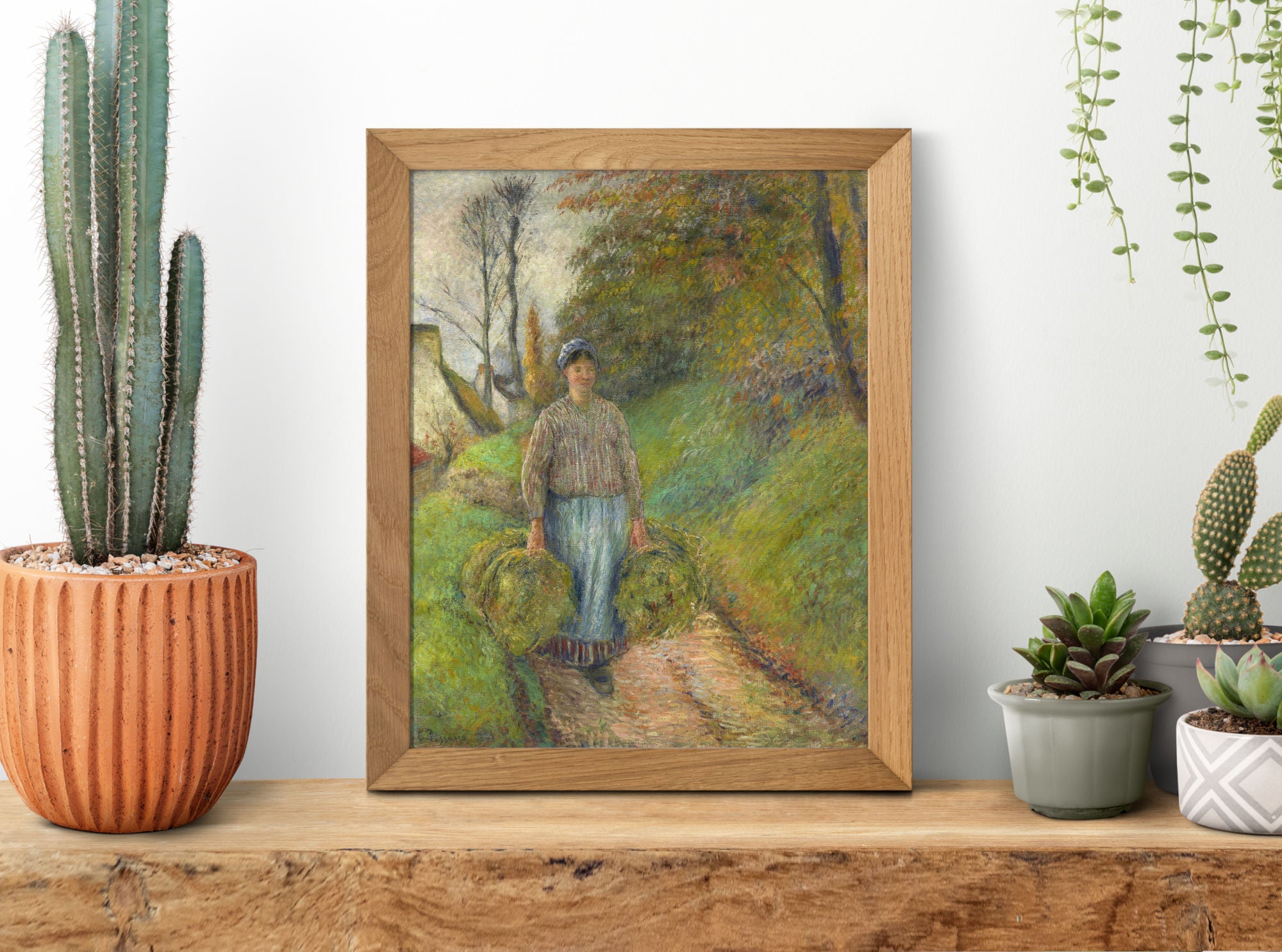 Framed painting of a person walking in a natural setting on a wooden shelf with plants.