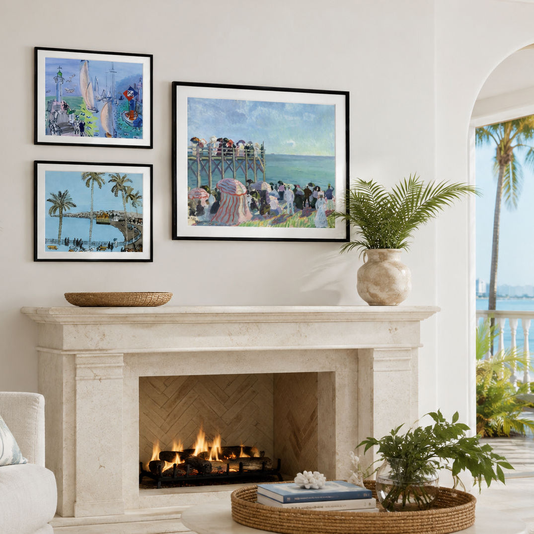 A styled interior scene showing three Raoul Dufy framed art prints displayed above a fireplace on a cream wall. The prints depict colorful beach and pier scenes, with a potted plant and decorative items on the mantel.