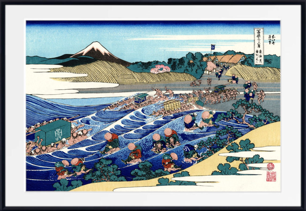 A framed Japanese ukiyo-e woodblock print depicting a river scene with boats, figures, hills, and Mount Fuji in the background, shown against a white mat and black frame.