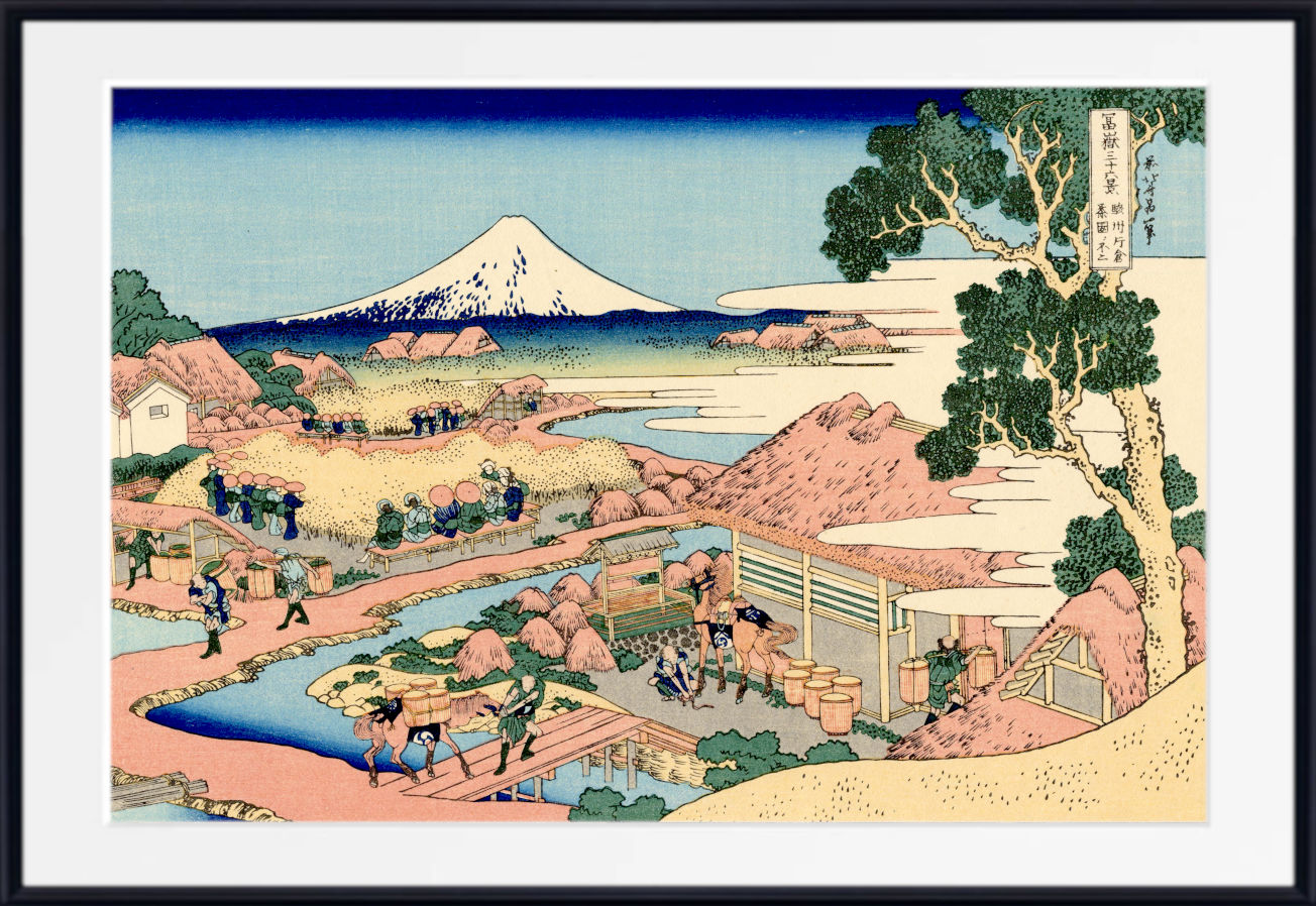 A framed Japanese ukiyo-e woodblock print depicting Mount Fuji, a river scene with figures, boats, and a large tree in the foreground, shown against a white mat and black frame.