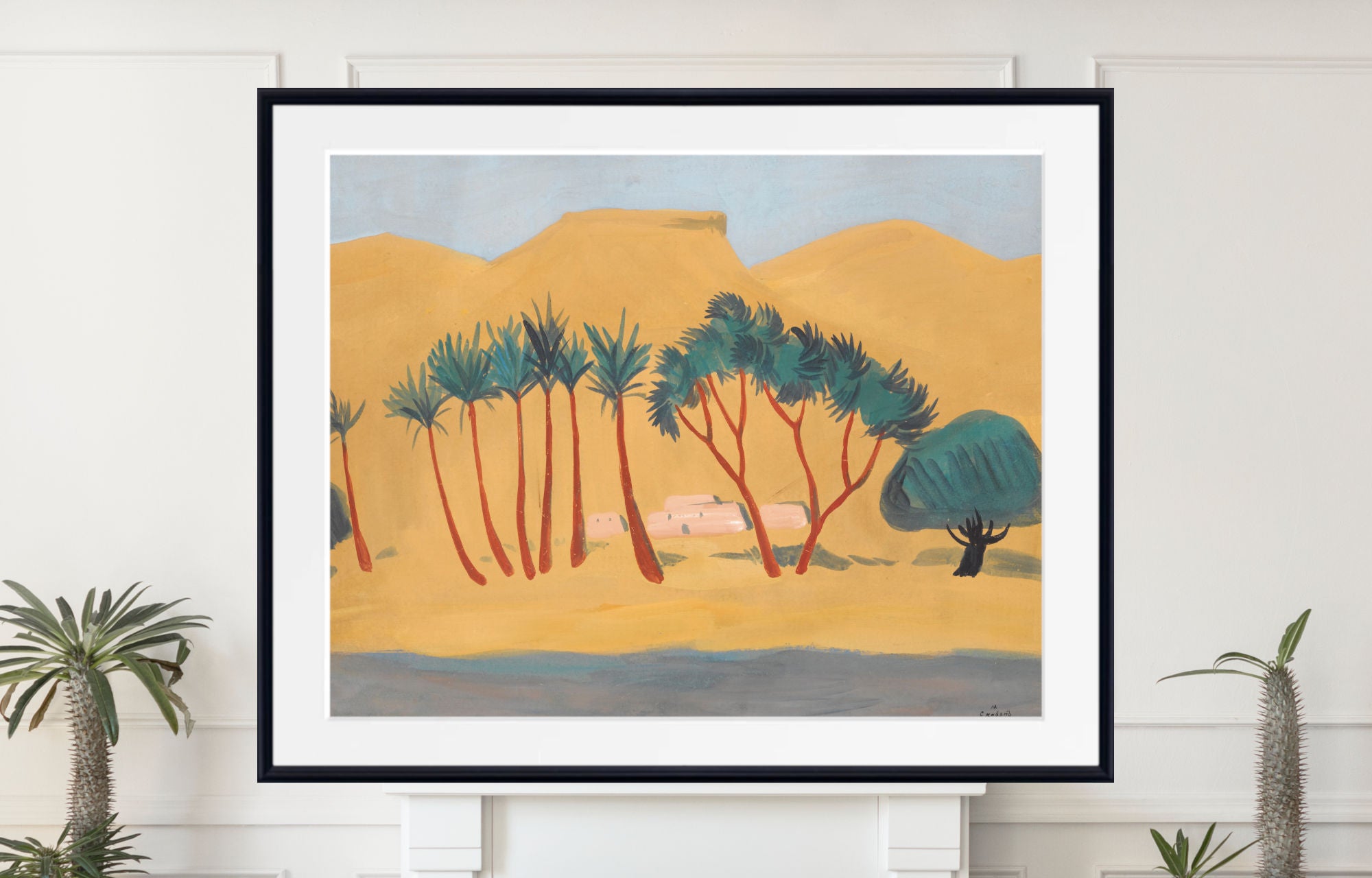 A framed art print depicting a stylized desert landscape with palm trees, mountains, and a pale blue sky, displayed on a white wall above a mantel with potted plants.