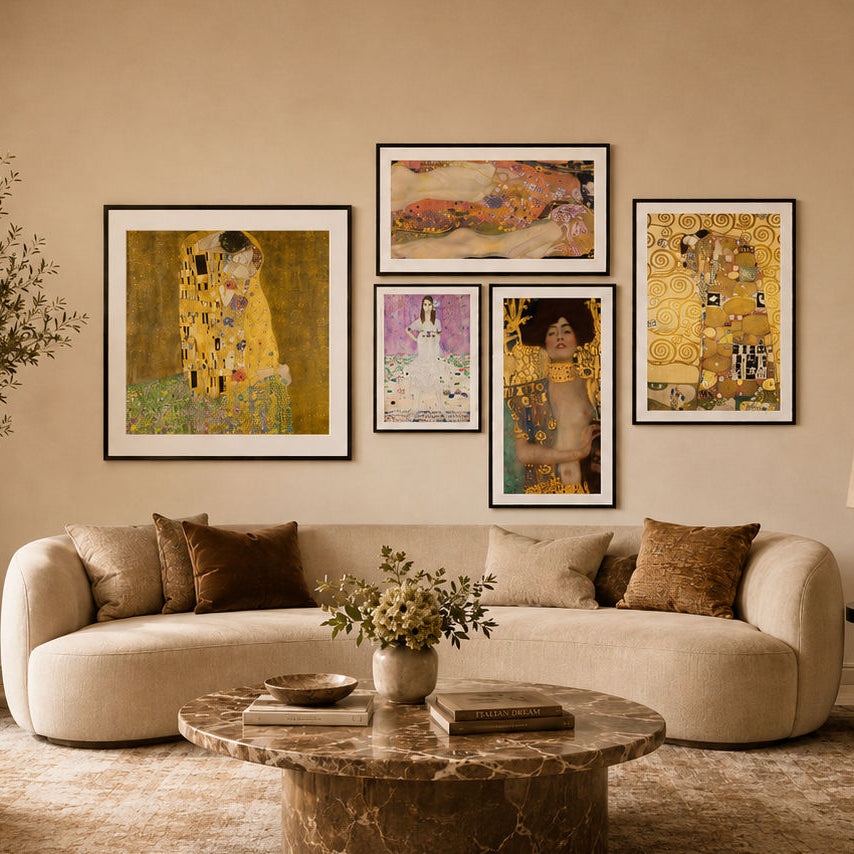 A styled living room with a curved cream sofa, a round marble coffee table, and a beige wall displaying five Gustav Klimt framed art prints in a gallery wall arrangement.