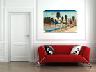 A framed Japanese-style landscape art print hangs on a white wall above a modern red sofa with black-and-white patterned pillows in a bright room.