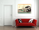 A framed Japanese-style art print depicting a traditional village scene with a thatched house and mountain, displayed on a white wall above a modern red sofa with black-and-white patterned pillows.