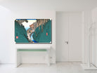 A framed Japanese ukiyo-e style art print depicting a mountain landscape with a river and figures, displayed on a white wall above a console table in a bright, modern white room.