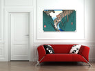 A framed horizontal art print depicting a traditional Japanese landscape with a winding river and mountains, displayed on a white wall above a modern red sofa with black and white patterned pillows.