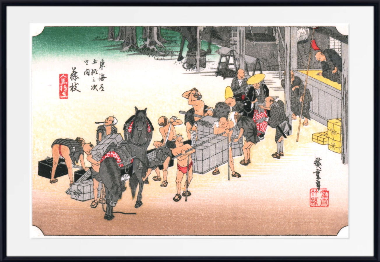 A framed Japanese-style art print depicting a street scene with people, horses, crates, and buildings, shown against a white background with a black frame border.
