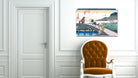 A framed Japanese-style art print depicting a fishing scene on a pier, displayed on a white paneled wall above an orange tufted armchair.