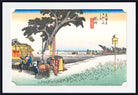 A framed Japanese ukiyo-e woodblock print showing a coastal scene with figures under a large tree near the shore, rendered in muted blue, beige, green, and black tones with a white mat and black frame.