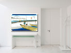 A framed Japanese ukiyo-e style art print depicting a fisherman in a boat, displayed on a white console table in a minimalist white room.