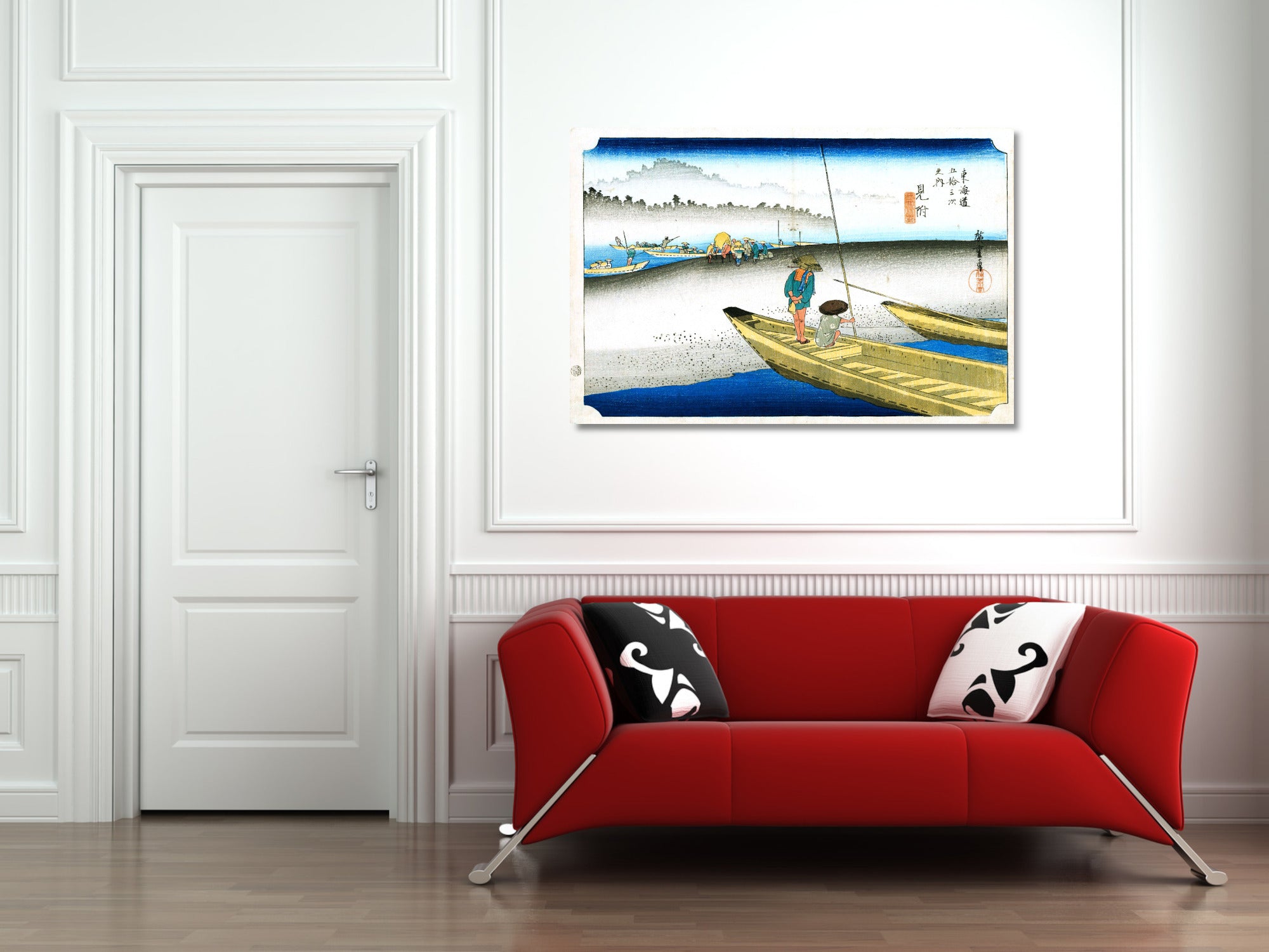 A framed Japanese-style art print depicting a fishing scene, displayed on a white wall above a modern red sofa with black and white patterned pillows in a living room setting.