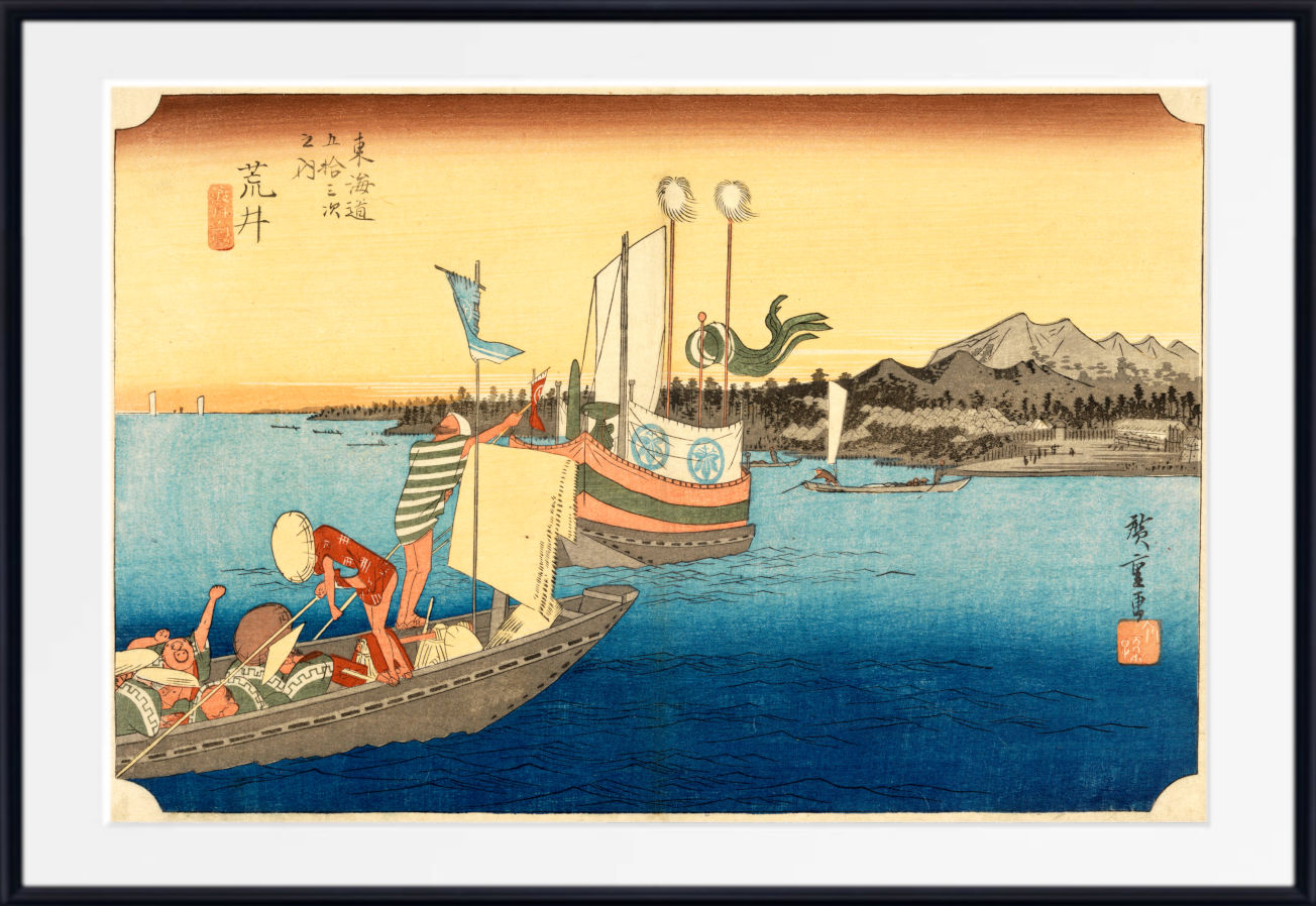 A framed Japanese-style art print showing a coastal scene with boats on blue water, mountains in the distance, and a warm yellow sky. The print is centered within a white mat and a black frame.