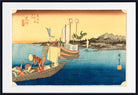 A framed Japanese-style art print showing a coastal scene with boats on blue water, mountains in the distance, and a warm yellow sky. The print is centered within a white mat and a black frame.