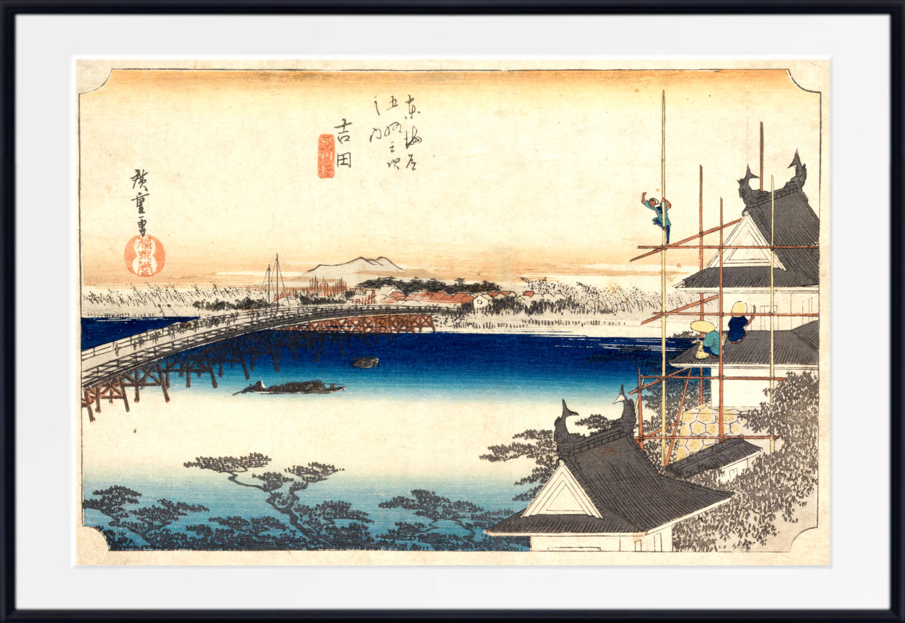 A framed Japanese ukiyo-e woodblock print depicting a snowy landscape with a bridge over blue water, traditional buildings, and figures on scaffolding, shown with a white mat and black frame.