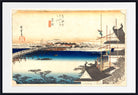 A framed Japanese ukiyo-e woodblock print depicting a snowy landscape with a bridge over blue water, traditional buildings, and figures on scaffolding, shown with a white mat and black frame.