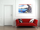 A framed art print of a Japanese ukiyo-e woodblock scene with boats and a harbor, displayed on a white wall above a modern red sofa with black and white patterned pillows.