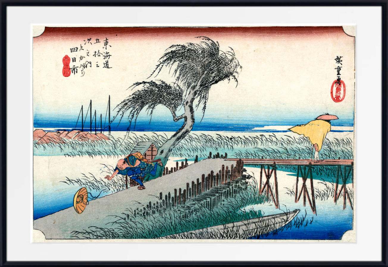 A framed Japanese ukiyo-e woodblock print showing a windswept willow tree, a pier, blue water, and a figure in a boat, presented with a white mat and black frame.