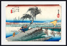 A framed Japanese ukiyo-e woodblock print showing a windswept willow tree, a pier, blue water, and a figure in a boat, presented with a white mat and black frame.