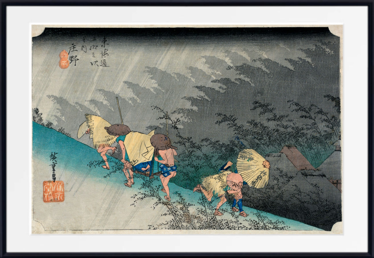A framed Japanese ukiyo-e woodblock print showing figures walking along a path in the rain, with a wide white mat and black frame around the artwork.