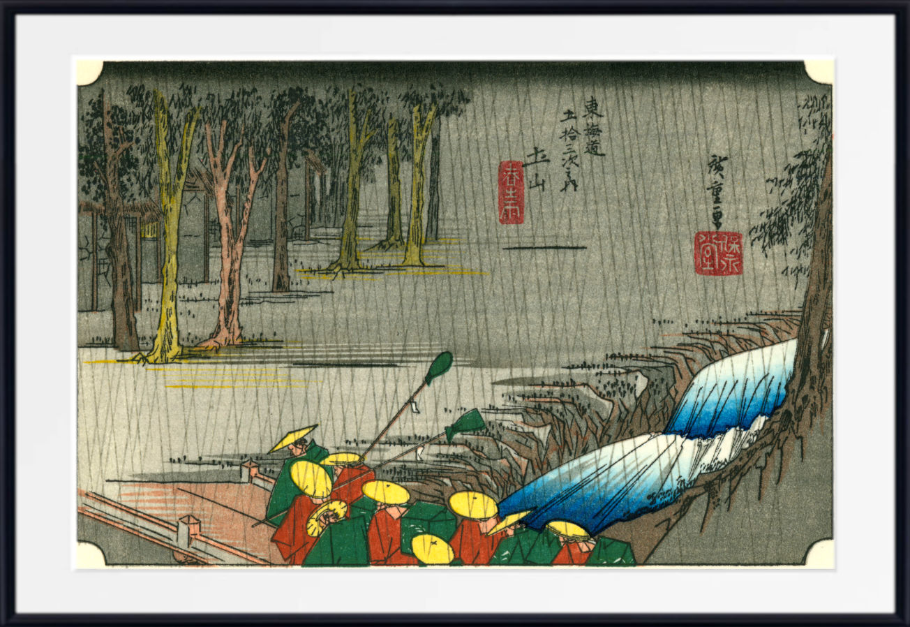 A framed Japanese-style art print showing a rainy outdoor scene with trees, a river or waterfall in blue tones, and small figures in red and yellow clothing. The print is presented with a white mat and black frame.