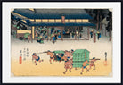 A framed Japanese ukiyo-e woodblock print depicting sumo wrestlers and a green cart in front of a temple, shown with a wide white mat and black frame.
