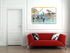 A framed Japanese ukiyo-e style art print depicting a street scene with figures and boats, displayed on a white wall above a modern red sofa with black and white patterned pillows.