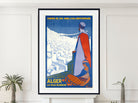A framed vintage-style travel poster of Algér, France, displayed on a white wall above a mantel with small potted plants. The poster features a stylized illustration of a figure in a red and white robe overlooking a white city under a dark blue night sky, with yellow text reading 'CHENIS DE TER PARIS-LYON-MEDITERRANÉE' and 'ALGER LA VILLE BLANCHE'.