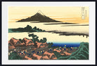 A framed Japanese-style art print depicting a coastal village with thatched-roof houses, a blue sea, and a mountain island in the distance, shown against a white mat and black frame.