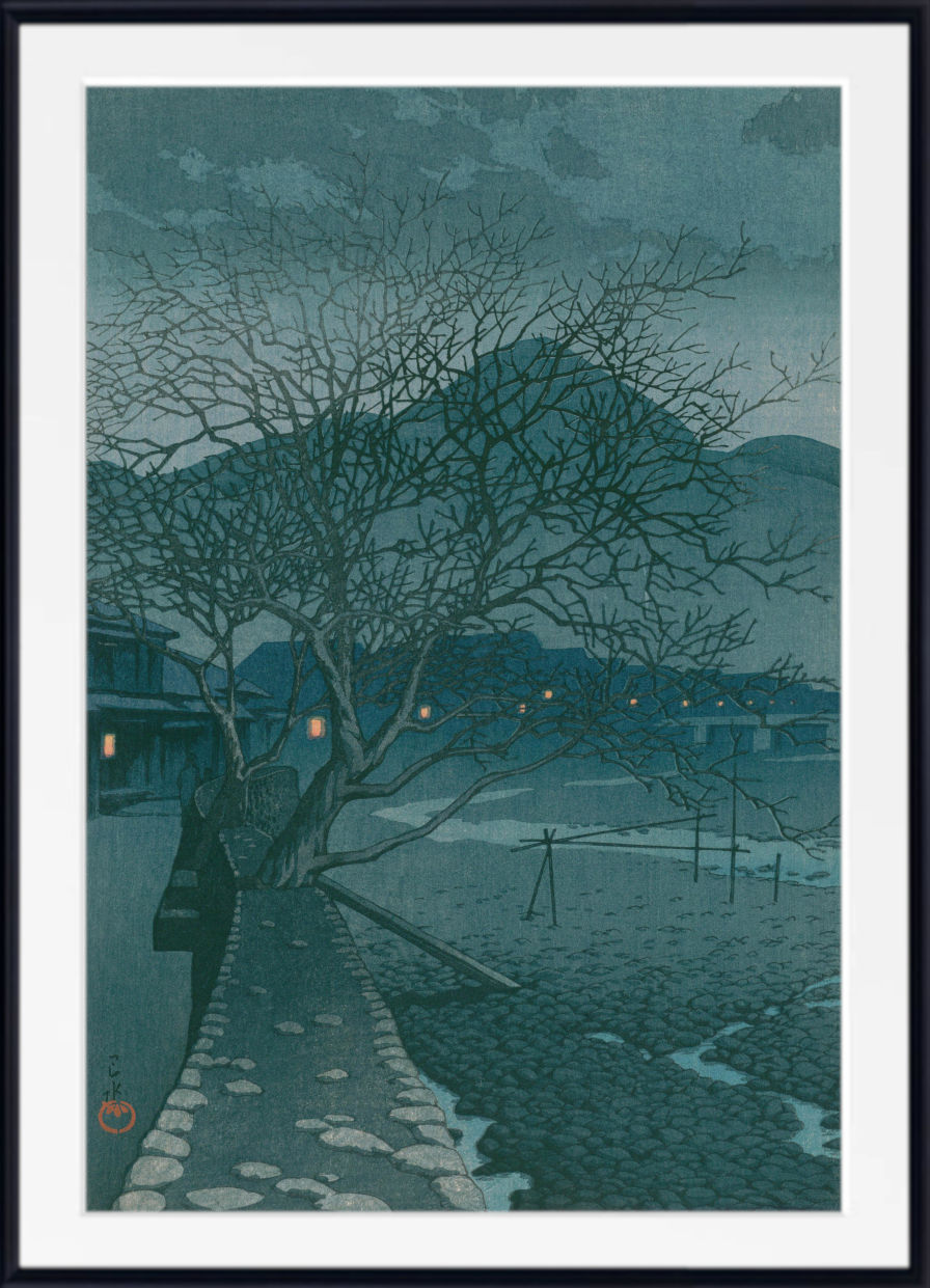 A framed Japanese-style art print depicting a moody night landscape with a bare tree, stone path, distant mountains, and small glowing windows, shown with a white mat and black frame.