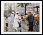 A framed art print depicting a vintage street scene with people, a woman in a white dress on a bicycle, and a flower cart, shown with a white mat and black frame.