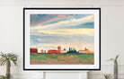 A framed art print featuring a landscape painting with a dramatic cloudy sky, red-roofed buildings, and a green field, displayed on a white wall above a mantel with potted plants.
