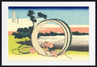 A framed Japanese-style art print showing a man working inside a large circular wooden structure near a lake, with trees, sky, and distant buildings. The print is presented with a white mat and black frame.