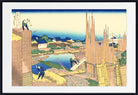 A framed Japanese ukiyo-e woodblock print showing workers constructing a brick wall beside a pond, with houses and bamboo in the background. The print is presented with a white mat and a black frame.