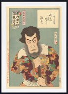 A framed Japanese ukiyo-e woodblock print showing a dramatic male figure in ornate dragon-patterned clothing against a muted green background, with calligraphic text panels in the upper right and red seals and calligraphy along the left side.
