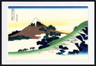 A framed Japanese-style landscape print showing a snow-capped mountain, green hills, trees, and small figures, presented with a white mat and black frame.