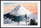 A framed Japanese-style art print depicting Mount Fuji with a snow-covered peak, dark shadowed slopes, and a warm peach and blue sky. The print is shown with a white mat and a black frame.