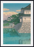 A framed Japanese-style art print depicting a stone castle wall, green trees, a pagoda, and blue water under a pale sky.