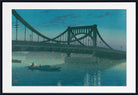A framed art print depicting a suspension bridge over calm blue water at dusk, with a small rowboat on the water and the bridge reflected below. The print is framed with a wide white mat and a black frame.